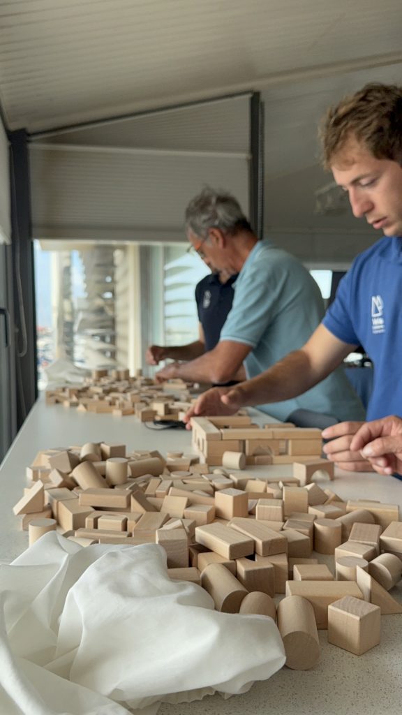 Participantes realizando una dinámica colaborativa con bloques de madera durante un taller.