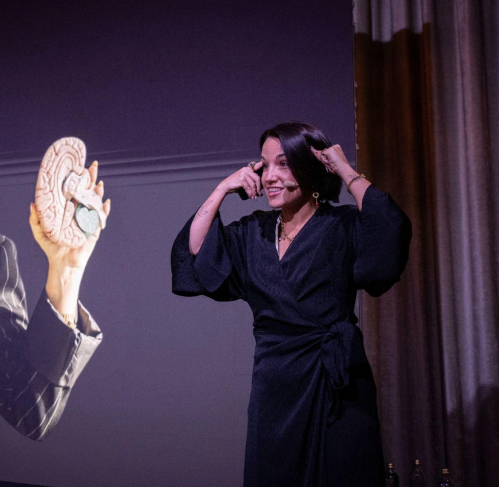 Gladys Kali impartiendo una conferencia de neurociencia con un modelo anatómico del cerebro.