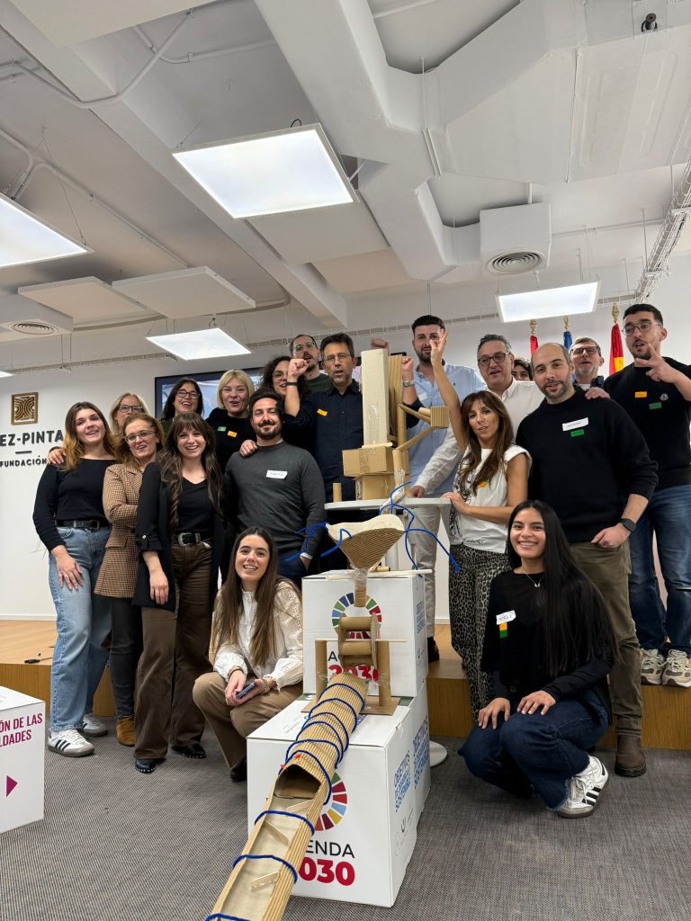 Participantes posando junto a un proyecto colaborativo desarrollado durante un taller.