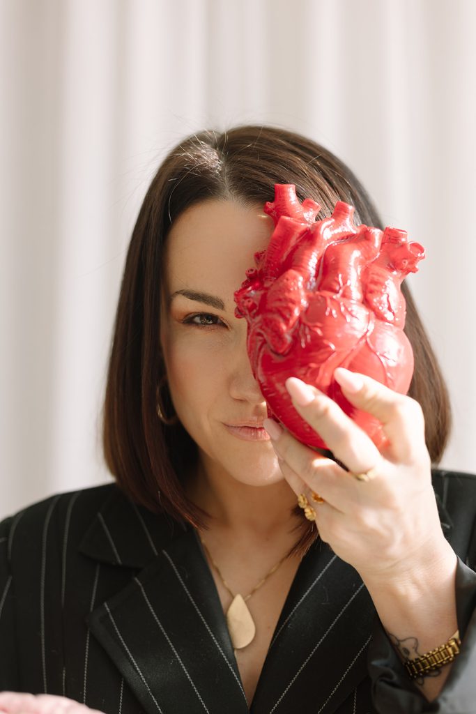 Gladys Kali sosteniendo un corazón anatómico como símbolo de la inteligencia emocional y el liderazgo.